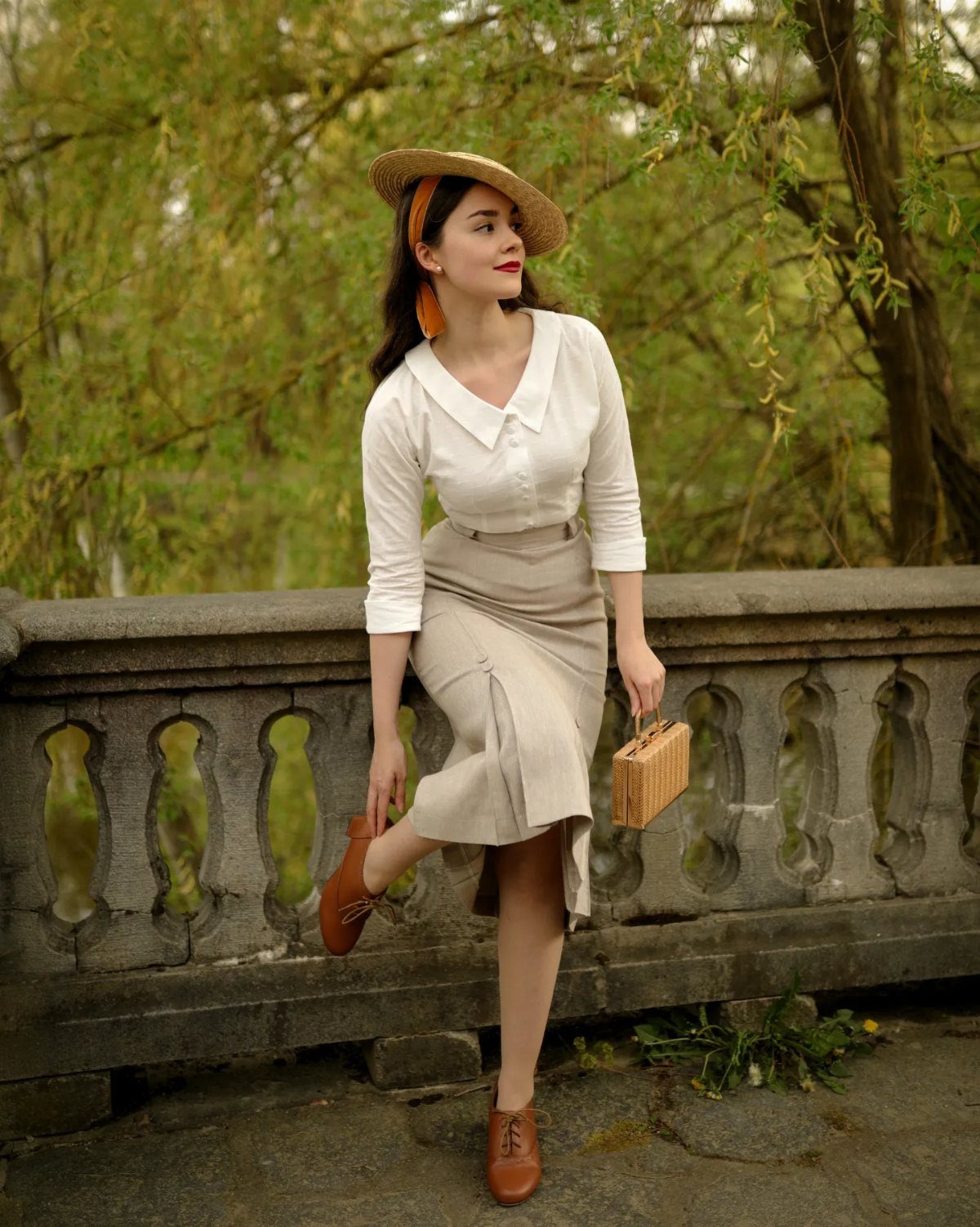 1950s Day Dress Ideas: 6 Retro Looks, From Gingham to Florals 3 Woman in a white shirt and beige pencil skirt posing by stone railing.