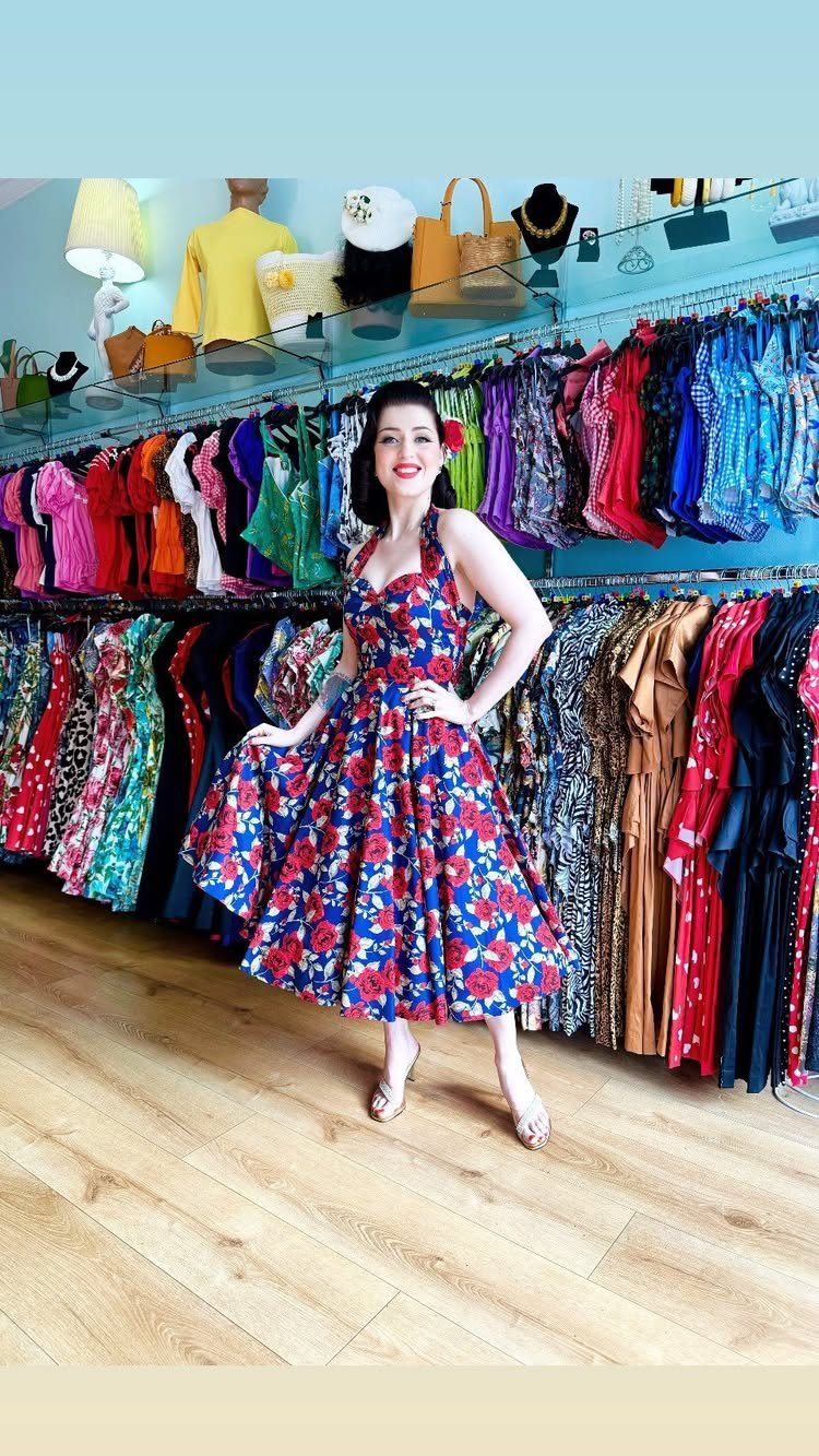 1950s Day Dress Ideas: 6 Retro Looks, From Gingham to Florals 4 Woman in a blue floral dress with a cinched waist and full skirt.