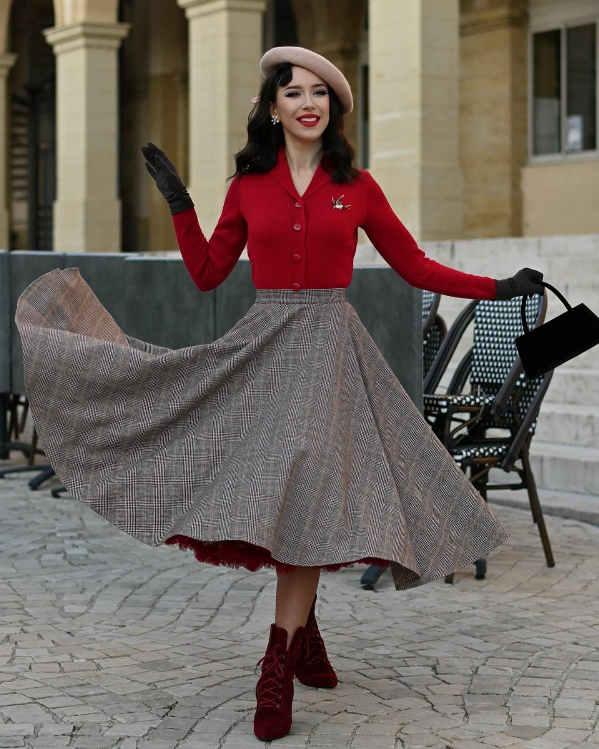 1950s Day Dress Ideas: 6 Retro Looks, From Gingham to Florals 2 Woman in red cardigan and swirling brown plaid full skirt wearing a beret.