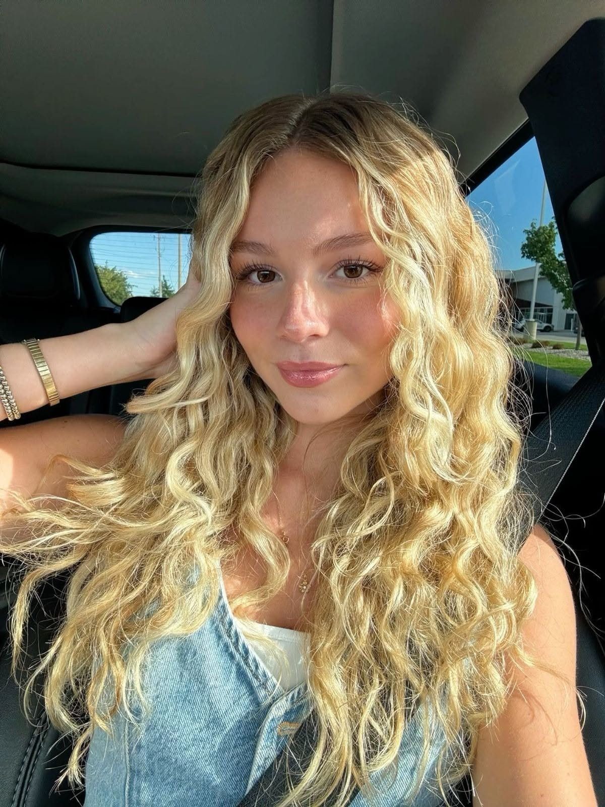 Young woman with long blonde wavy hair sitting in a car
