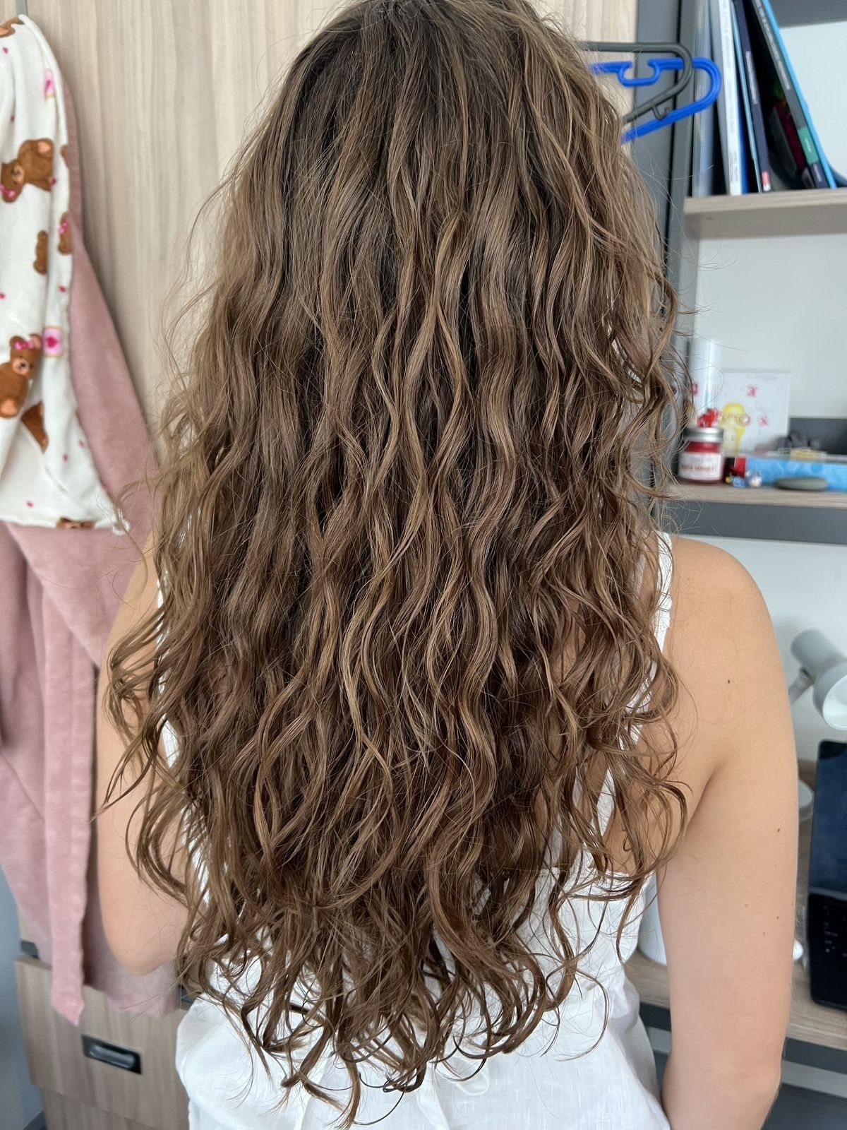 Long wavy brown hair seen from behind on a person wearing white.