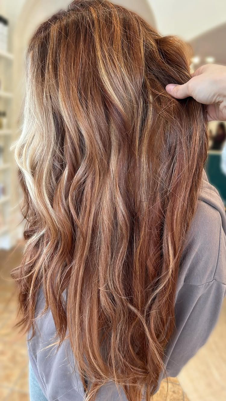 3 Color Hair Ideas: 15 Looks from Burnt Orange to Emerald 6 Long wavy auburn hair with blonde highlights being touched by a hand.