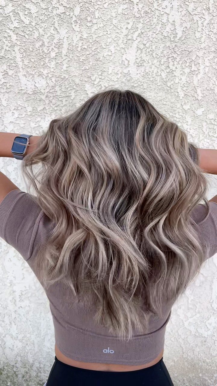 3 Color Hair Ideas: 15 Looks from Burnt Orange to Emerald 9 Wavy ash blonde and taupe hair seen from behind against a white wall.