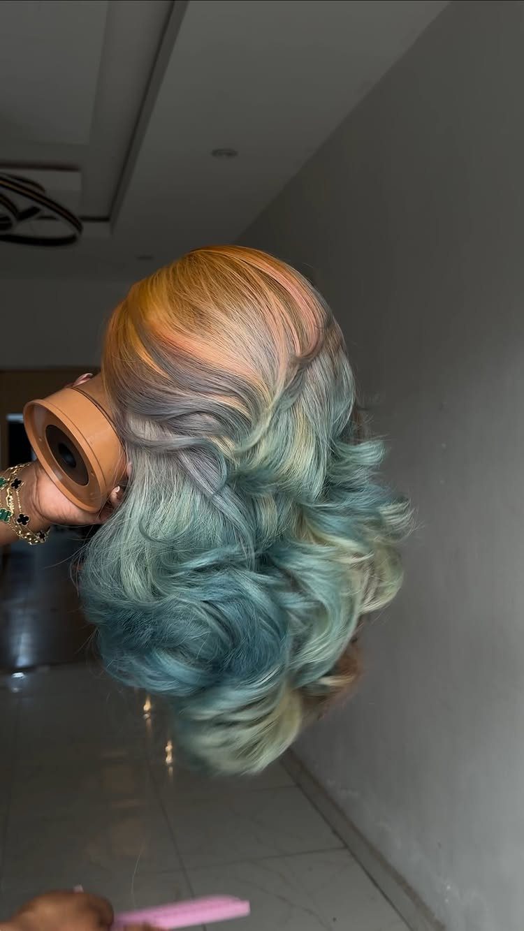3 Color Hair Ideas: 15 Looks from Burnt Orange to Emerald 7 Wavy multicolored hair with a gradient of orange, pink, purple, and blue-green tones.