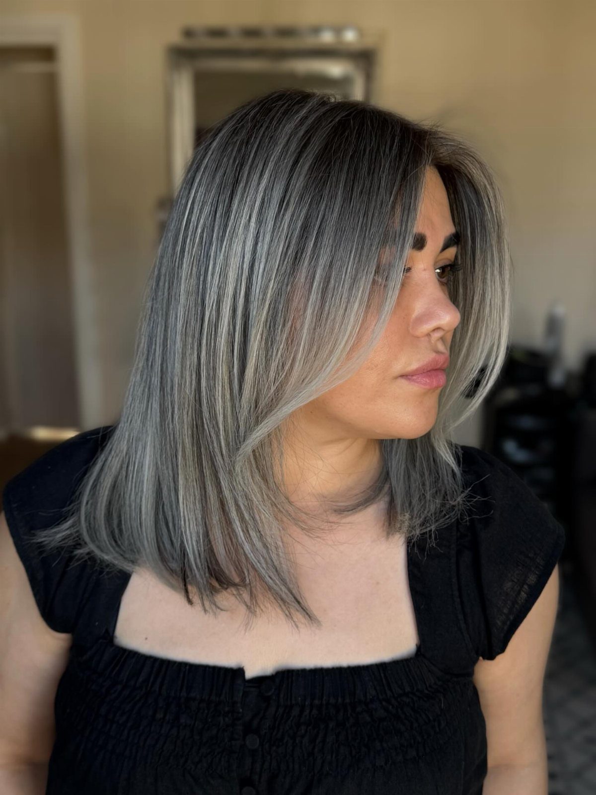 3 Color Hair Ideas: 15 Looks from Burnt Orange to Emerald 4 Woman with shoulder-length smoky silver and ash gray hair wearing a black top.