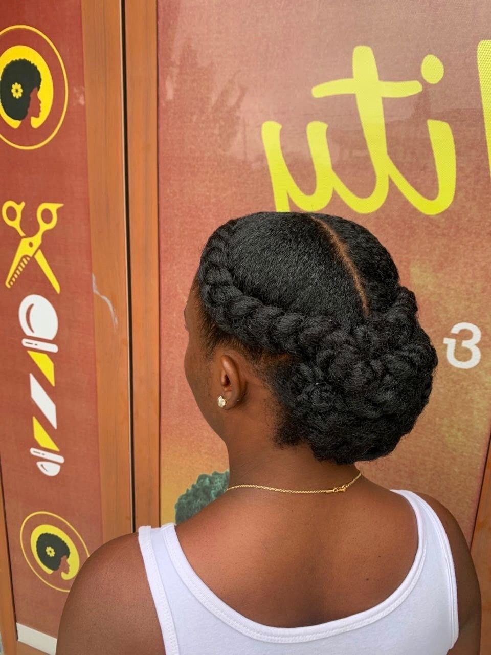 Woman with black hair styled in a thick braided crown updo.