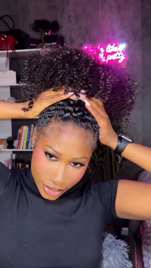 Woman with dark skin wearing a high puff hairstyle with tight curls.