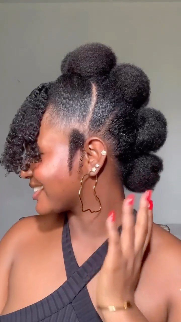 Woman with 4c hair styled in voluminous puffs and a curly front fringe.
