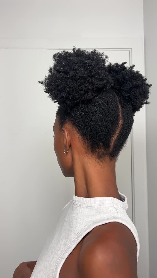 Person with 4C curly hair styled into two voluminous space buns on top.