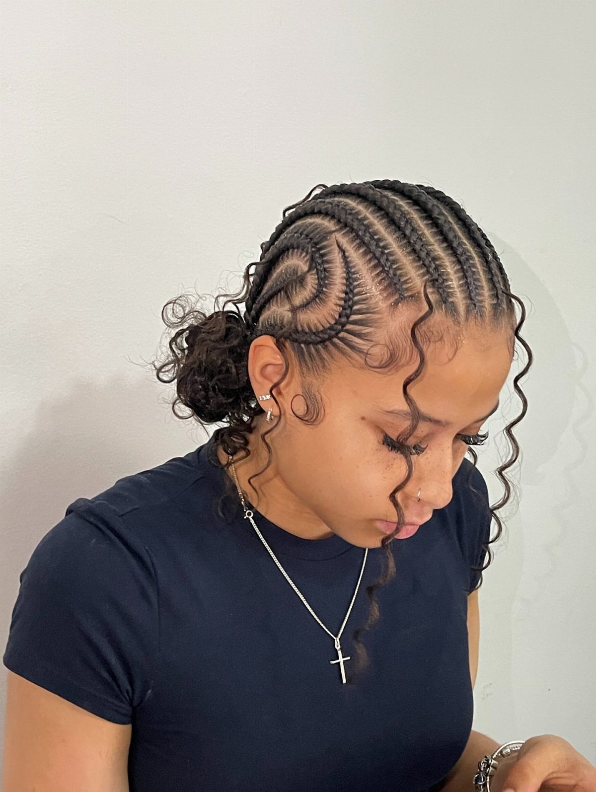 Woman with stitch braids in a geometric pattern and curly tendrils framing her face.