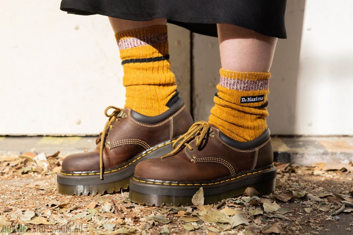 Brown distressed leather platform shoes with yellow stitching and mustard striped socks.