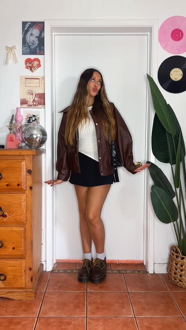 Woman wearing brown leather platform casual shoes, a leather jacket, and a black skirt.
