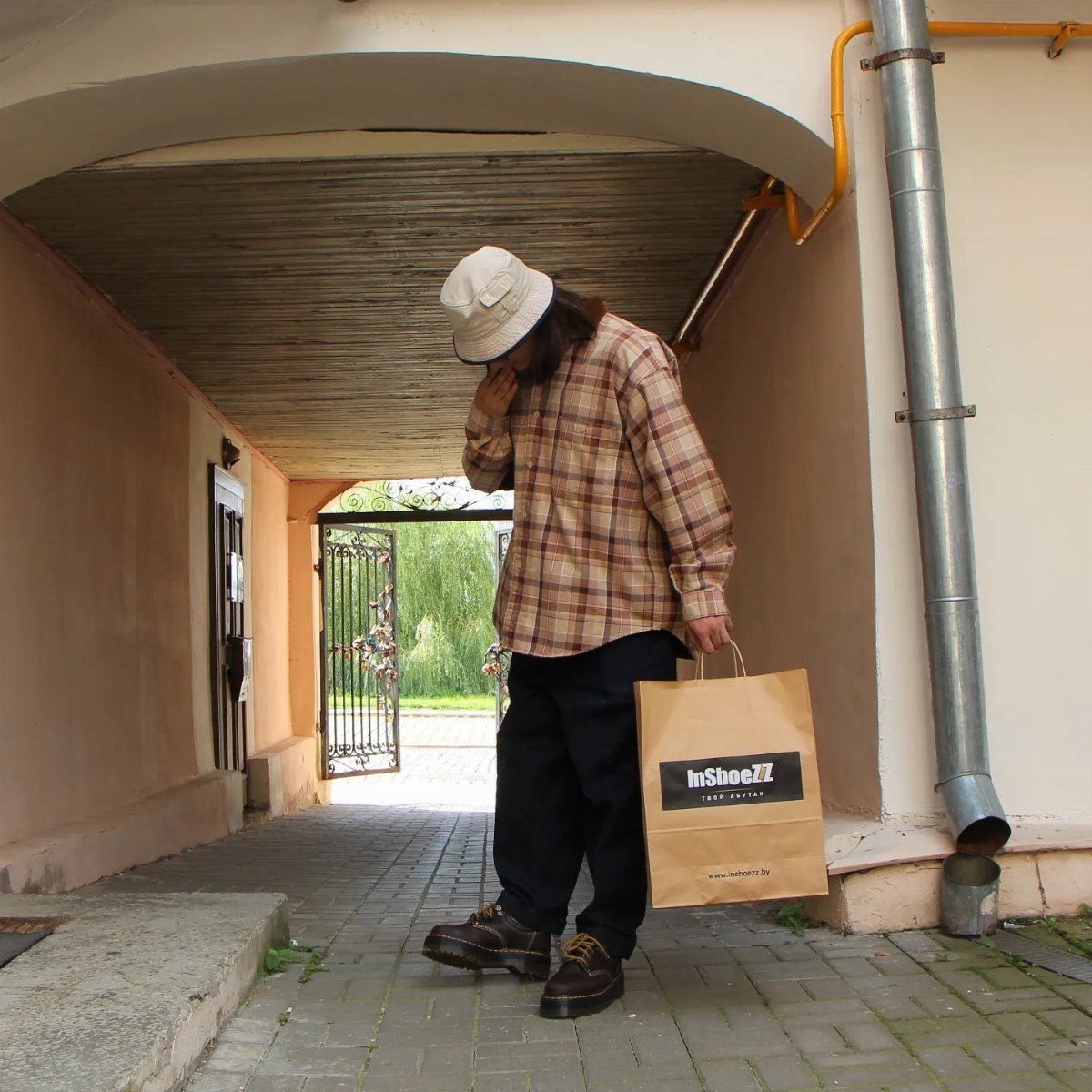 Person in plaid shirt and black pants wearing brown leather platform casual shoes