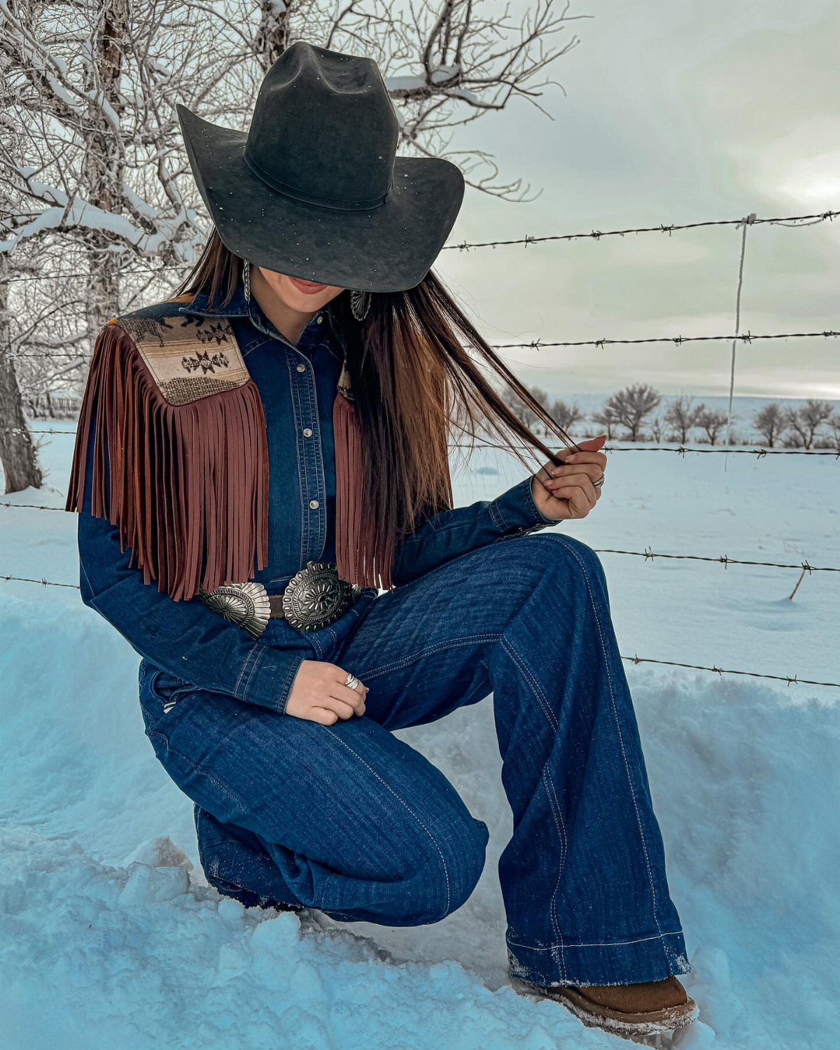 8 Outfit Ideas for 90s Country Style with Denim 2 Woman in cowboy hat and fringed suede vest crouching in snowy field