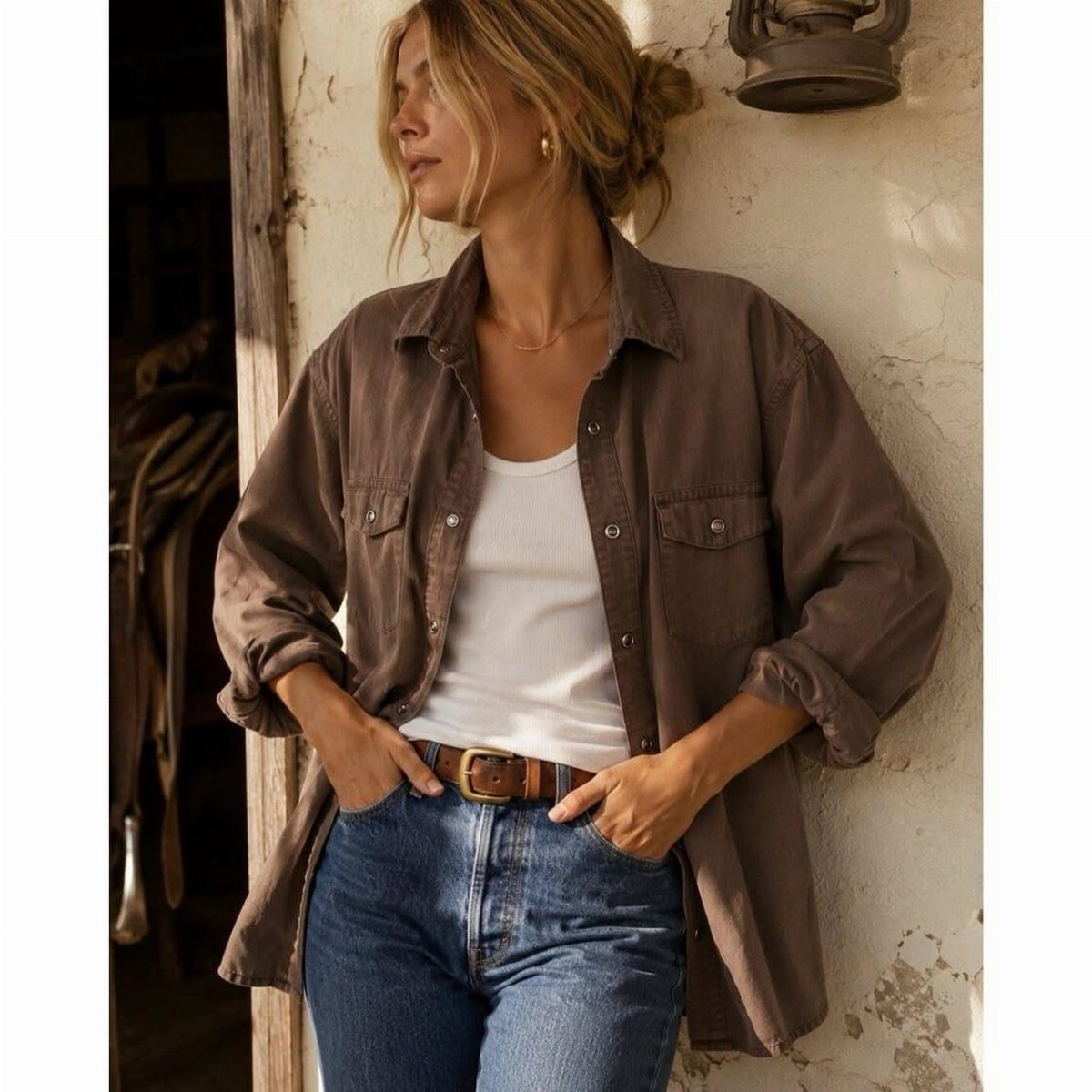 8 Outfit Ideas for 90s Country Style with Denim 6 Woman wearing an oversized brown button-down shirt over a white tank top and jeans.
