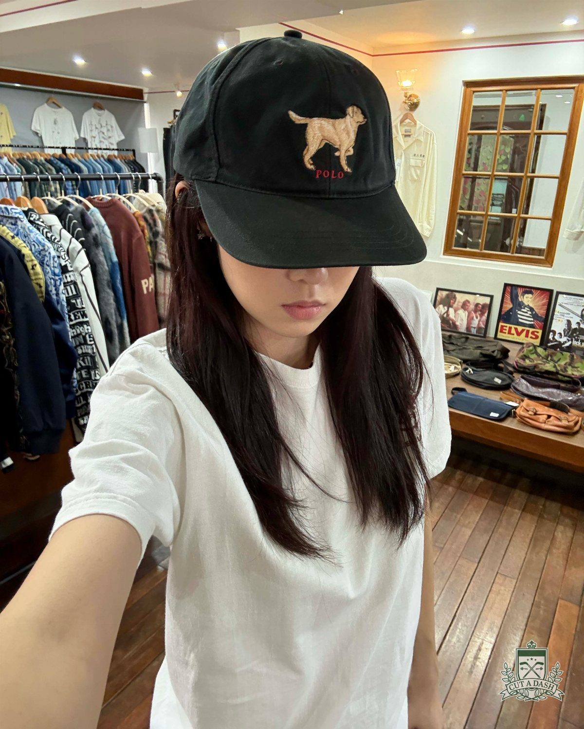 90s Vintage Streetwear Ideas: 9 Pieces Worth Wearing 6 Person wearing a black baseball cap with gold dog embroidery and white t-shirt.