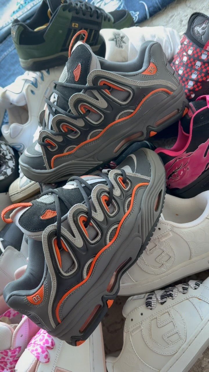 90s Vintage Streetwear Ideas: 9 Pieces Worth Wearing 8 Grey and orange chunky sneakers piled among other colorful athletic footwear.