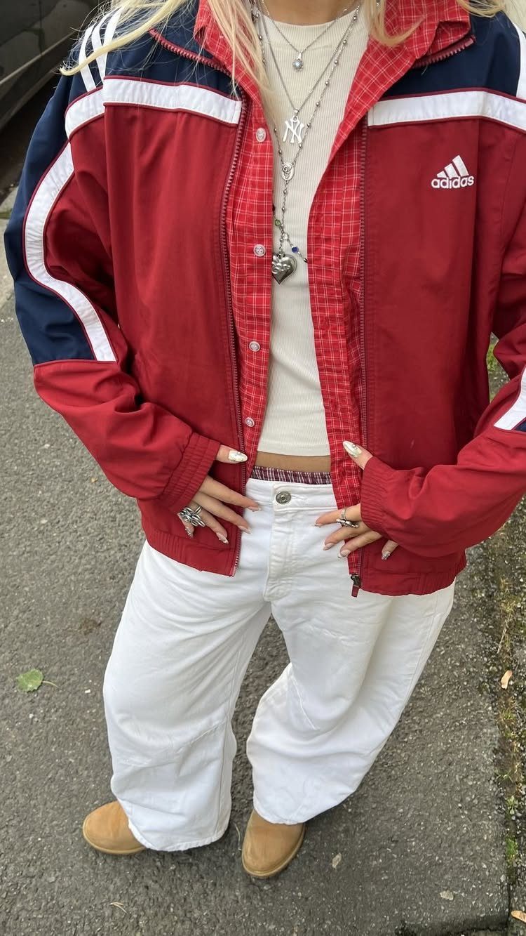 90s Vintage Streetwear Ideas: 9 Pieces Worth Wearing 3 Person wearing a red Adidas vintage windbreaker with white wide-leg trousers and necklaces.