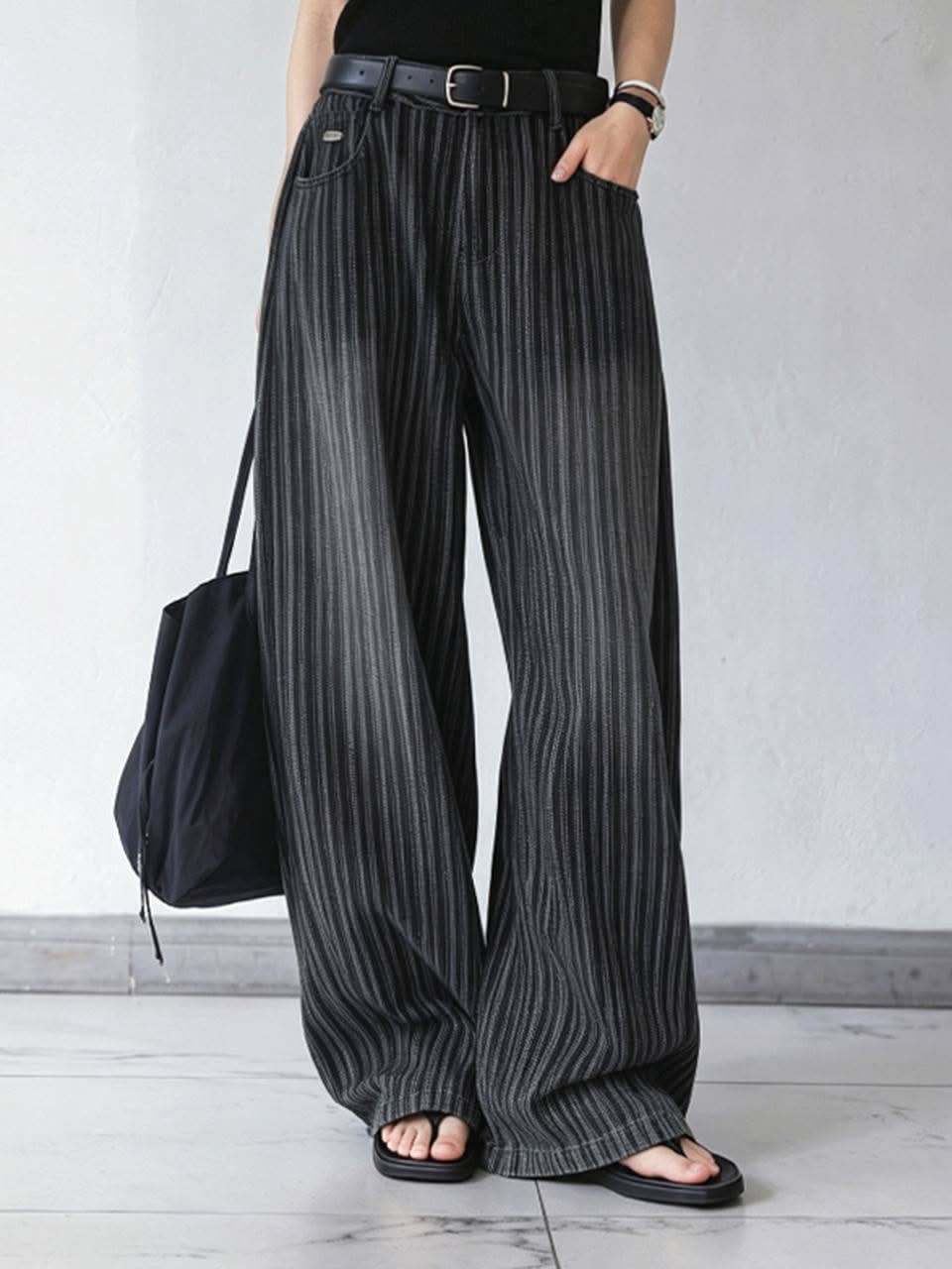 90s Vintage Streetwear Ideas: 9 Pieces Worth Wearing 5 Wide-leg trousers with vertical grey and black stripes paired with a black belt.