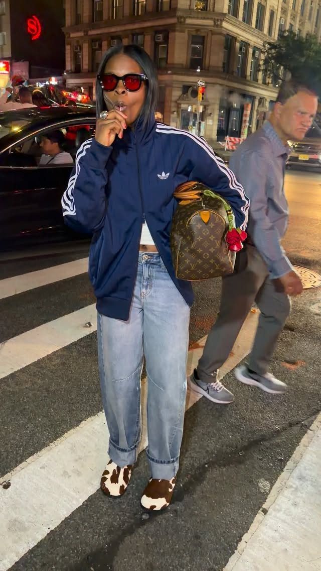 Woman wearing a navy blue Adidas track jacket and light blue jeans on street