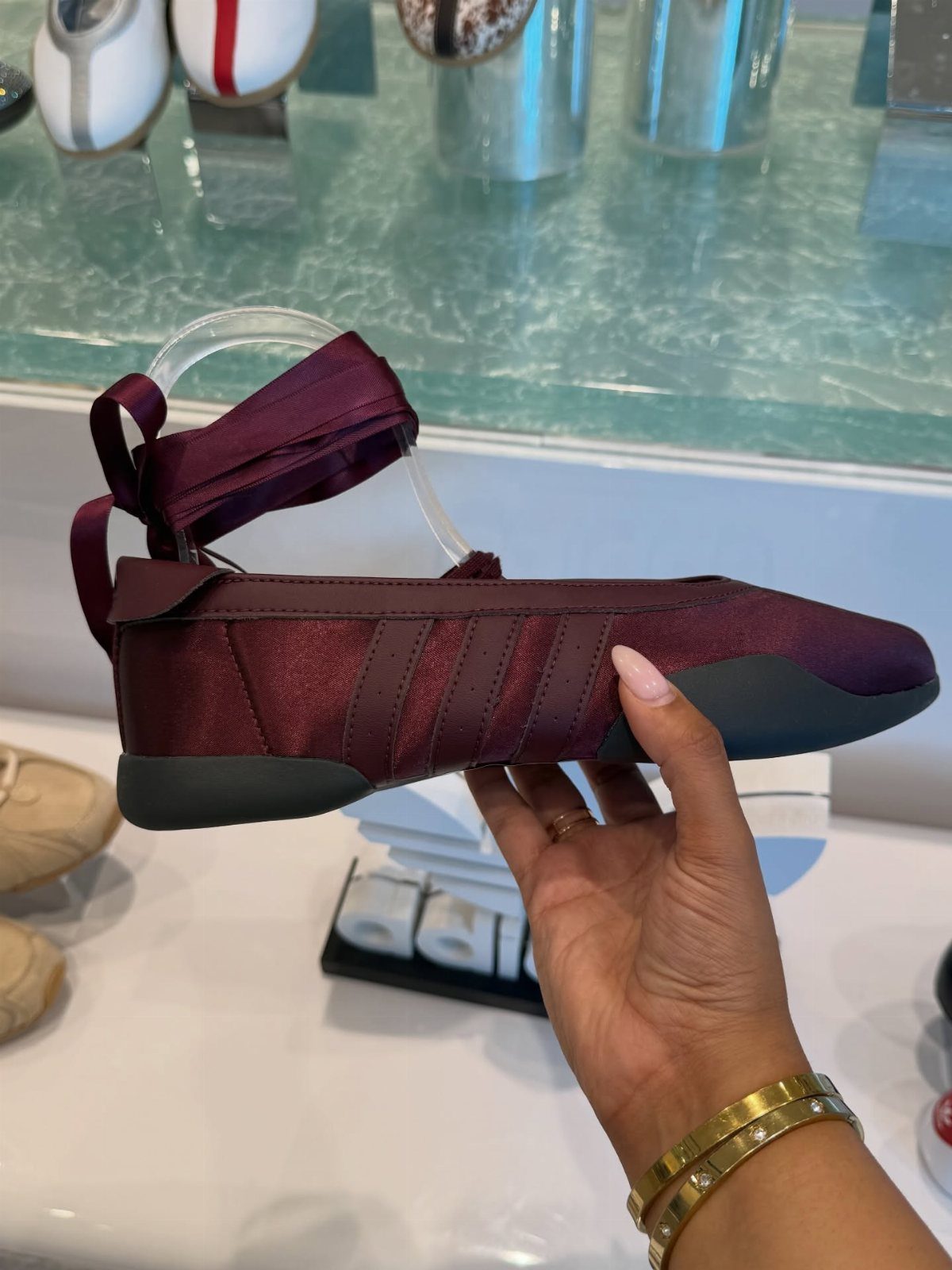 Adidas Taekwondo Ballerina Looks and Styles: 5 Ideas 1 Burgundy satin adidas Taekwondo Mei Ballet sneakers held by a hand in a store.