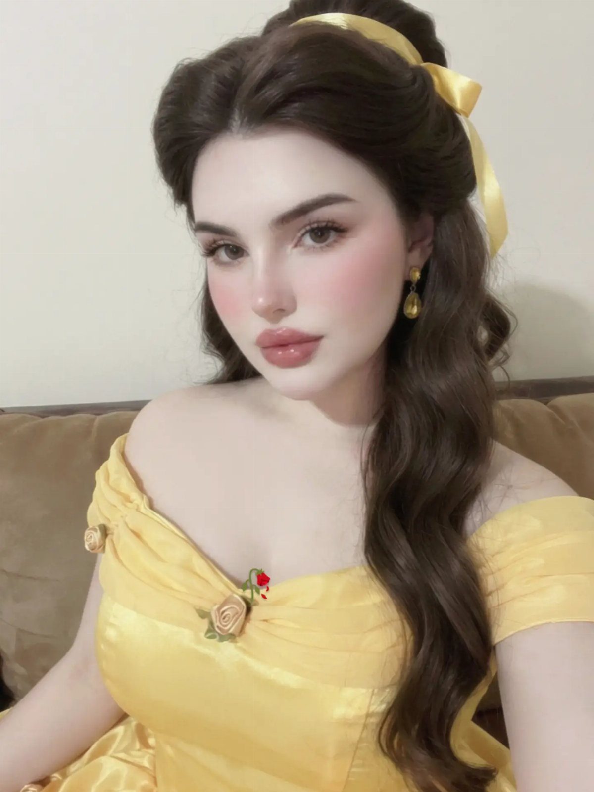 Woman wearing a yellow Belle-inspired gown with rose details and hair ribbon.