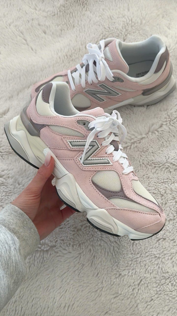 Pink and grey chunky New Balance sneakers resting on a white fluffy rug