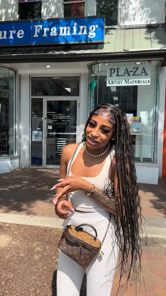20 African Hair Styles Braids 14 Woman with long boho braids and curly ends posing in front of a store.