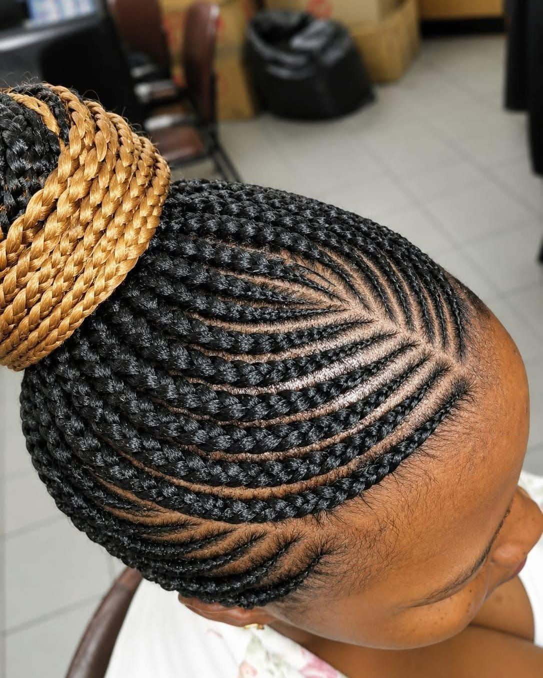 20 African Hair Styles Braids 15 Black cornrows styled into a large golden-brown braided bun on top of head.