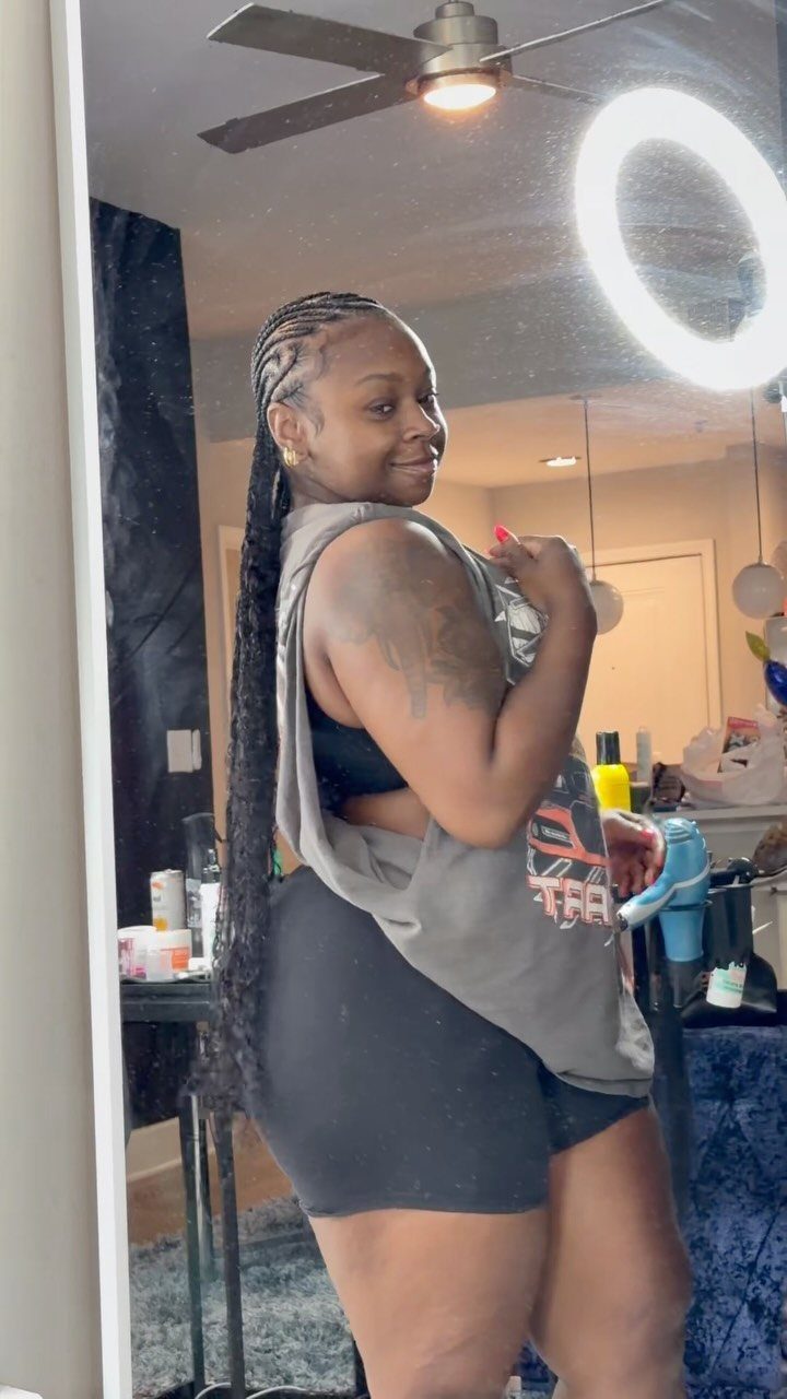 20 African Hair Styles Braids 20 Woman with long dark feed-in braids posing in a mirror wearing casual clothes.