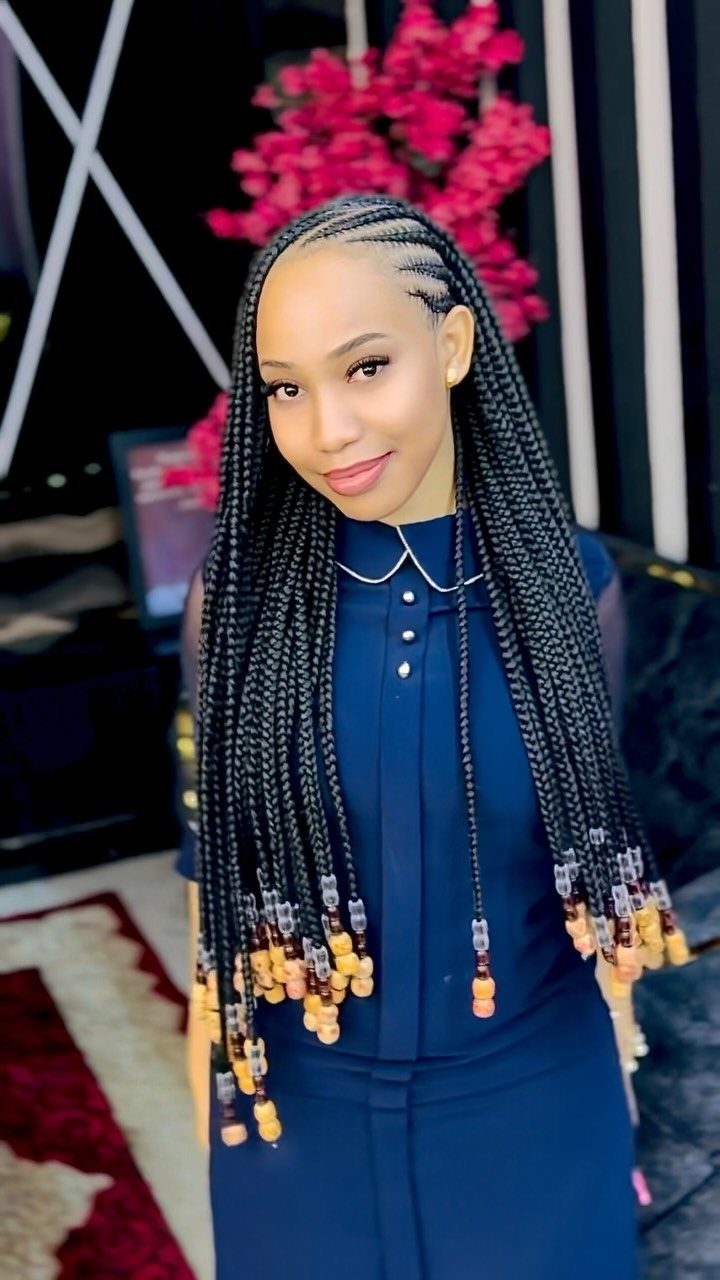 20 African Hair Styles Braids 16 Woman with stitch braids and beaded ends wearing a navy blue dress.