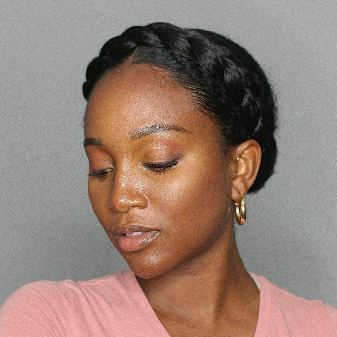 Afro Hair 4c Style Ideas: 19 Looks From Cornrows to Locs 17 Woman with a braided crown hairstyle wearing a pink shirt and gold earrings.