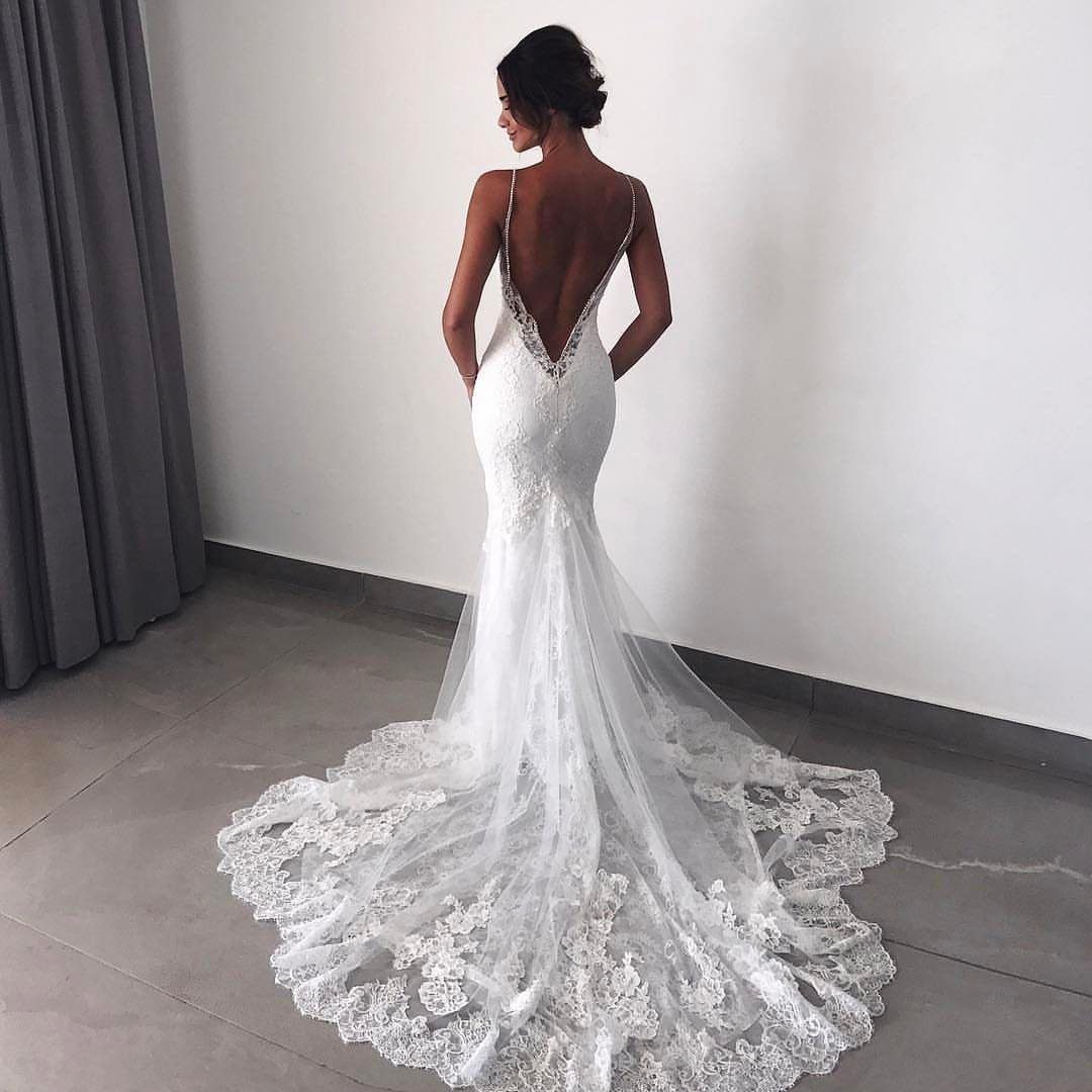 Woman in a white lace wedding dress with a deep open back and train.