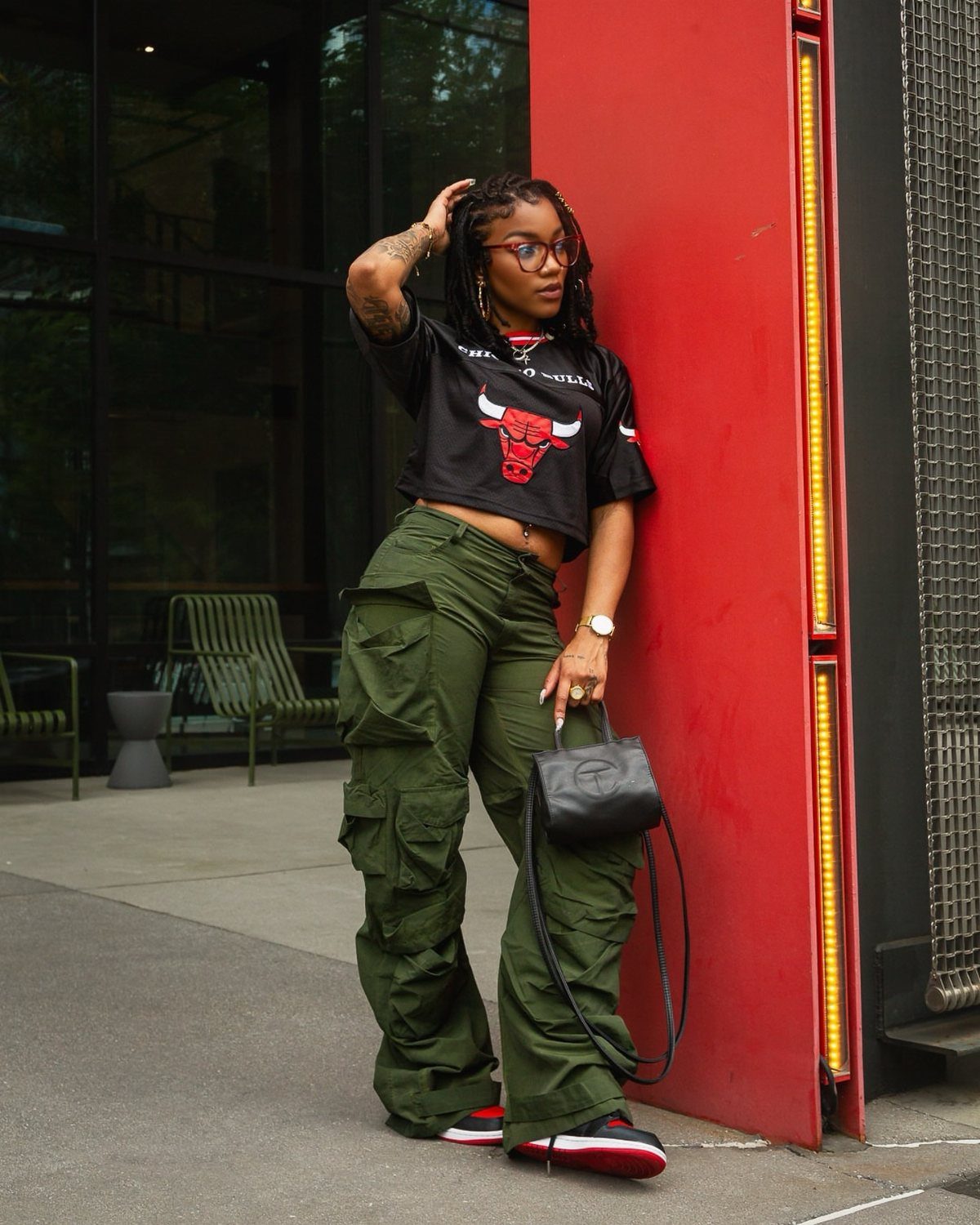 Woman wearing olive green cargo pants and a cropped black graphic t-shirt.