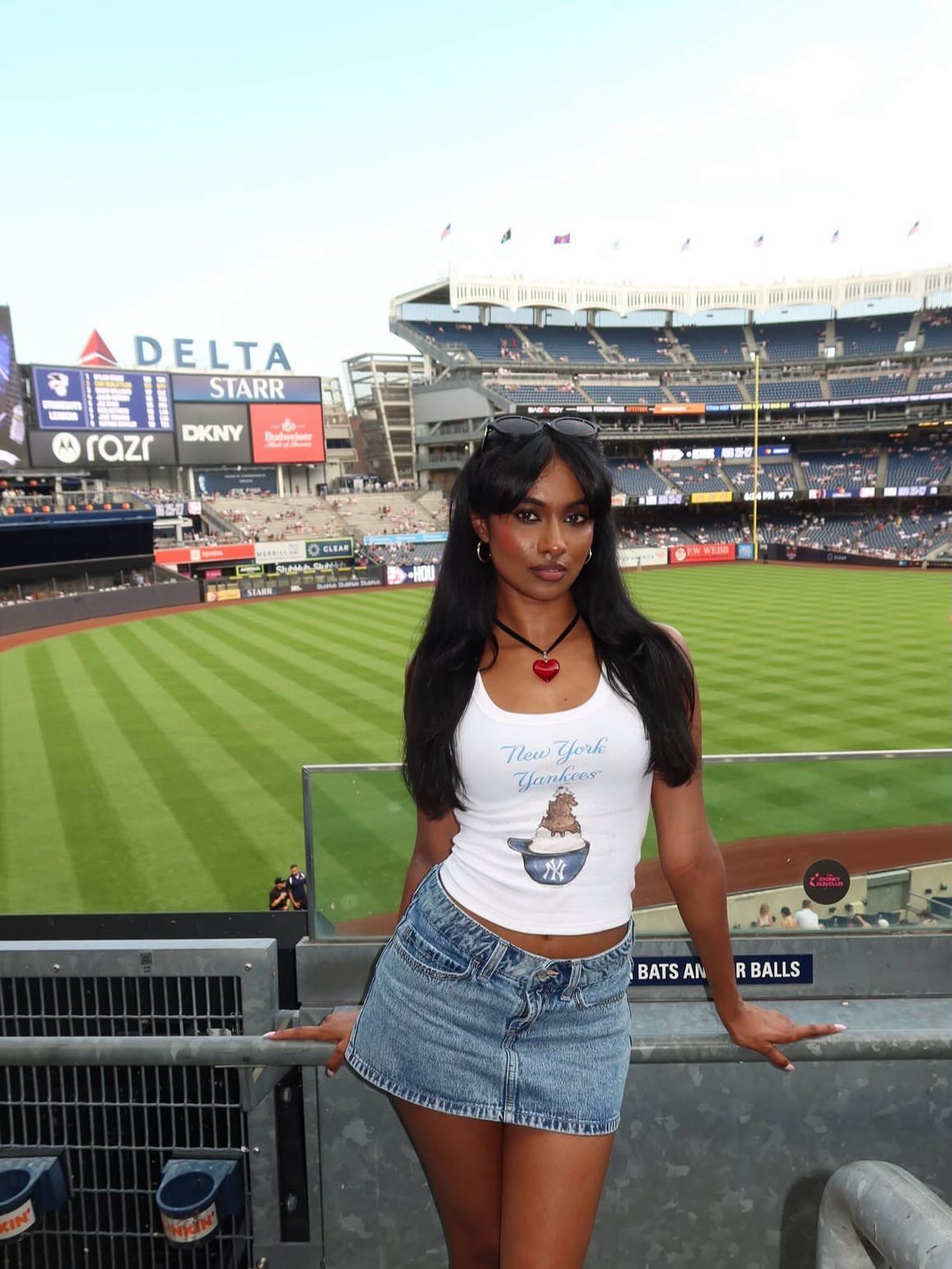 Woman in a Yankees crop top and denim mini skirt at a baseball stadium
