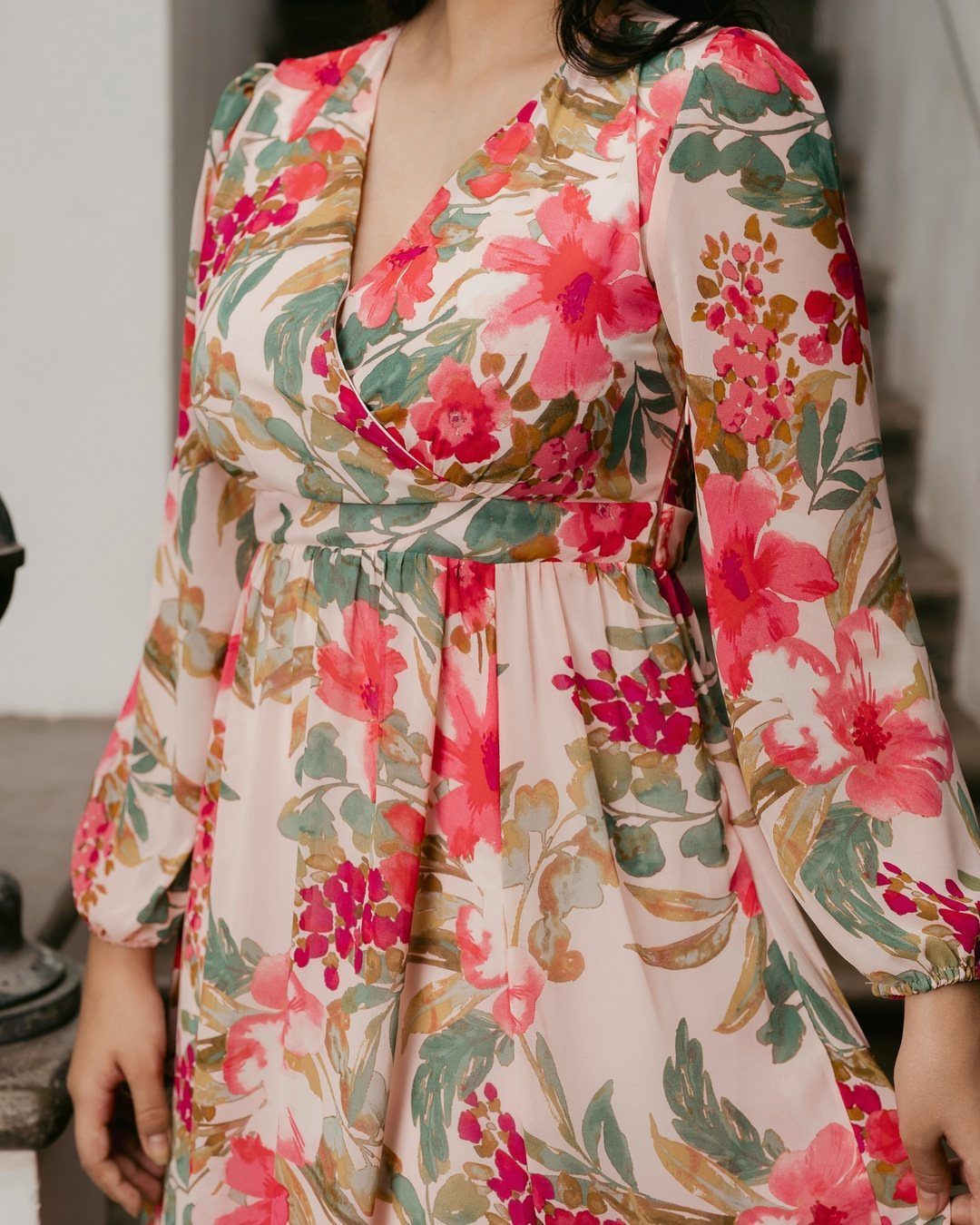 Woman wearing a light pink gown with a vibrant red and green floral print.
