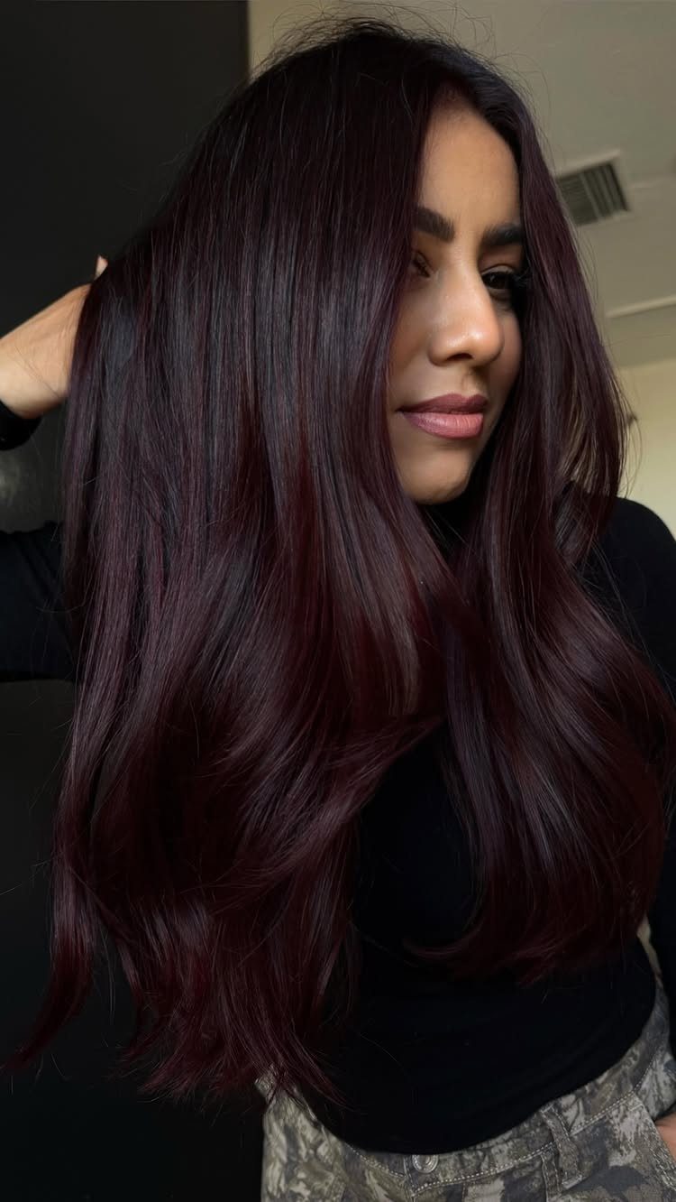 5 Black Cherry Hair Ideas for Deep, Glossy Color 1 Woman with long wavy hair in a deep black cherry burgundy color.