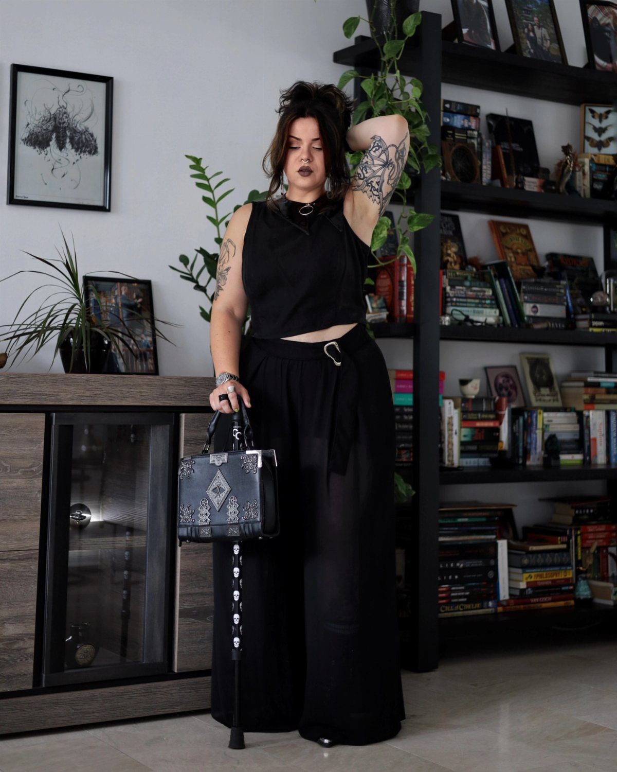 5 Blackout Party Outfits for a Night of Head-to-Toe Black 1 Woman in black crop top and wide-leg trousers posing in a home library