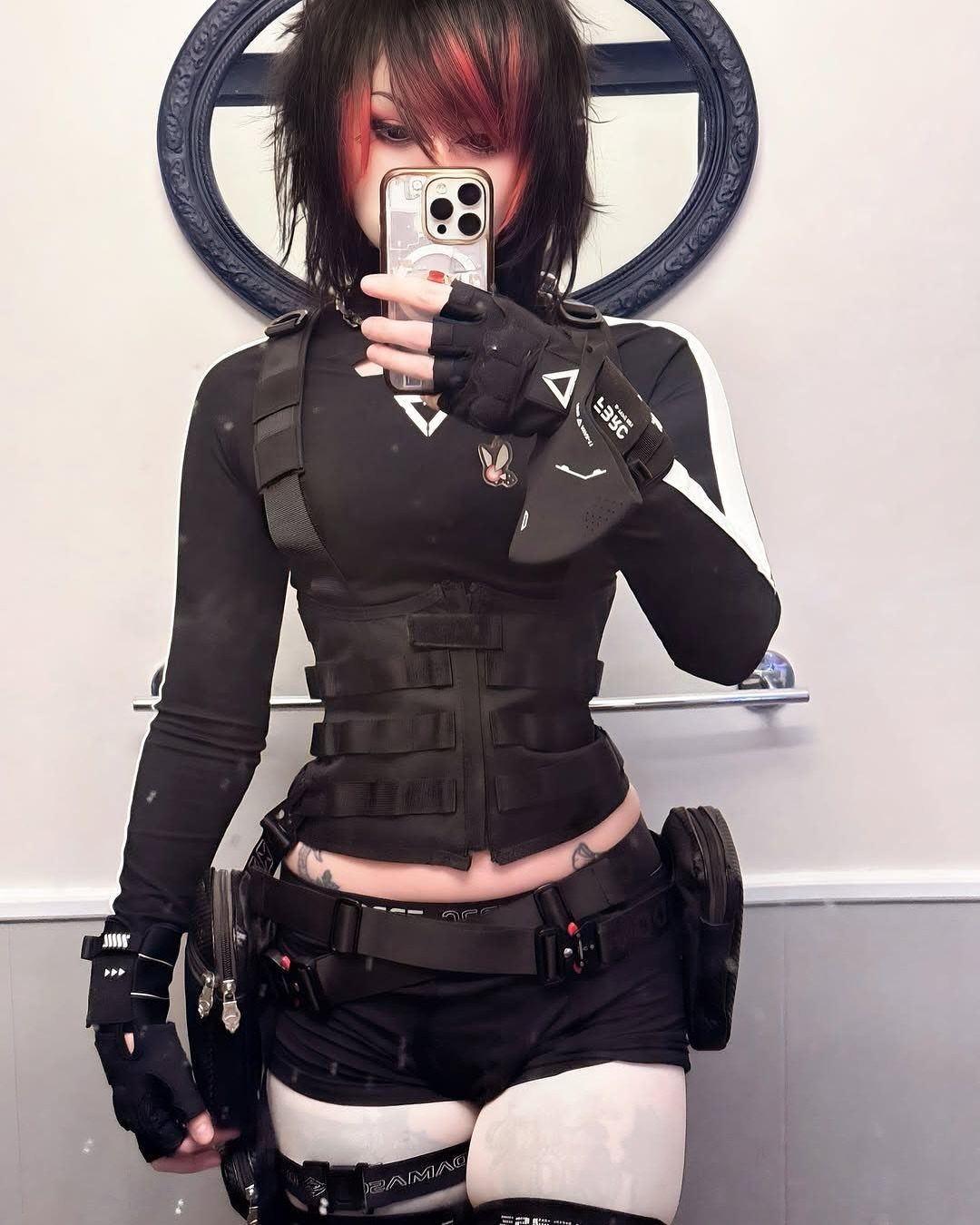 5 Blackout Party Outfits for a Night of Head-to-Toe Black 2 Person in black tactical outfit with buckled vest and utility belt taking selfie