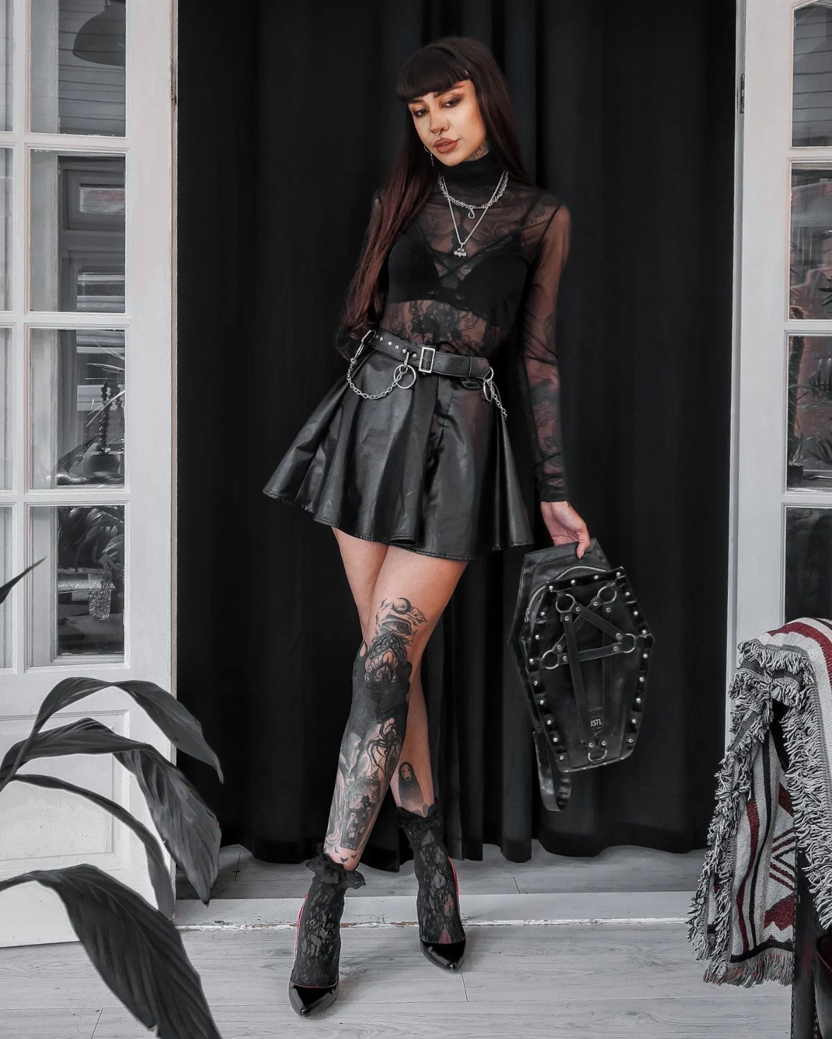 5 Blackout Party Outfits for a Night of Head-to-Toe Black 3 Woman wearing an all-black outfit with a leather skirt and sheer top.