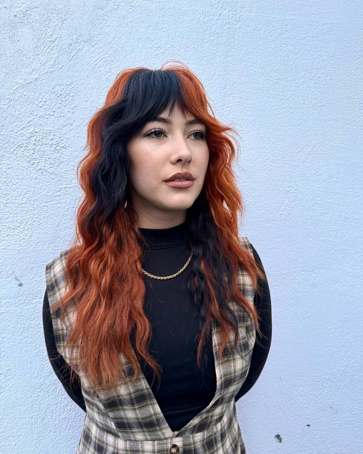 Woman with long wavy hair dyed in bold black and orange color blocks.