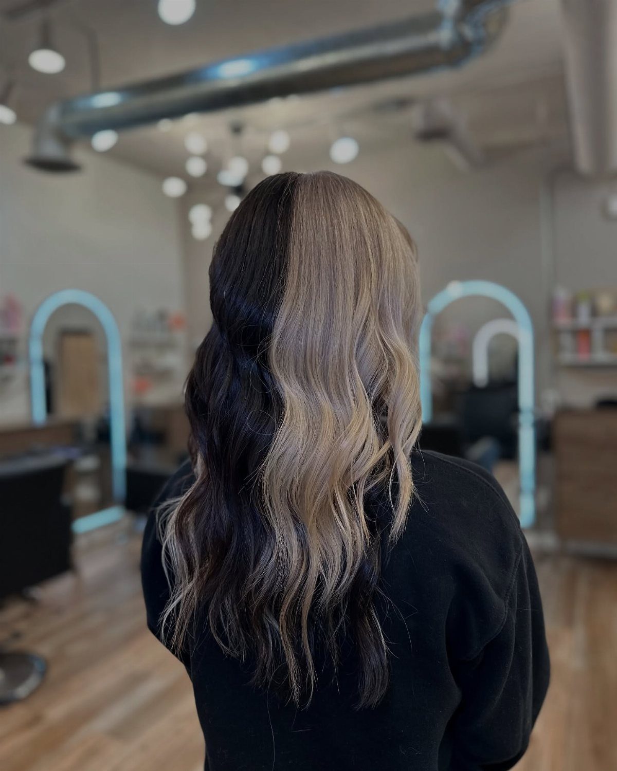 Person with long wavy hair split vertically into dark brown and blonde colors.