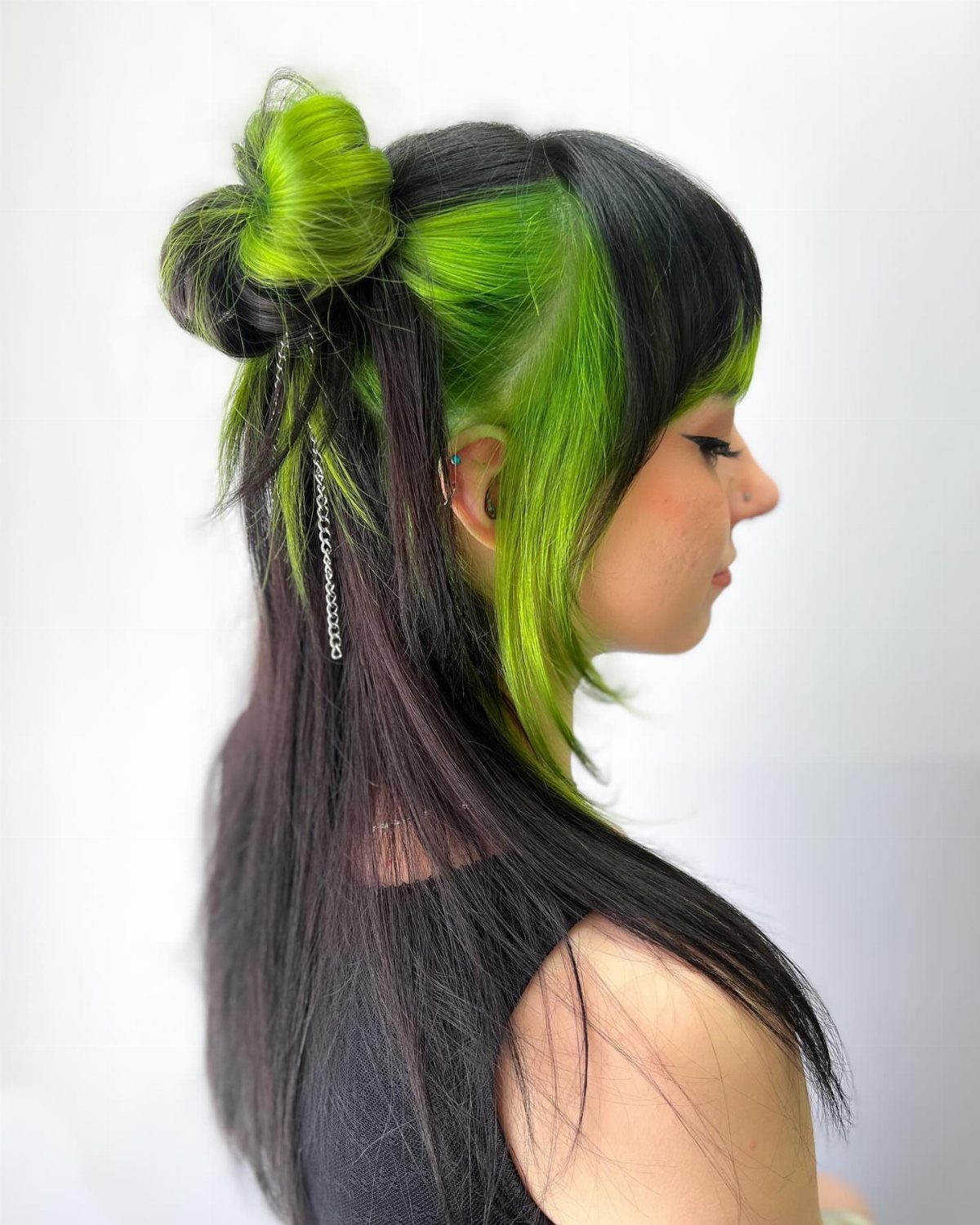 Person with black hair and a bold lime green color-blocked side section.