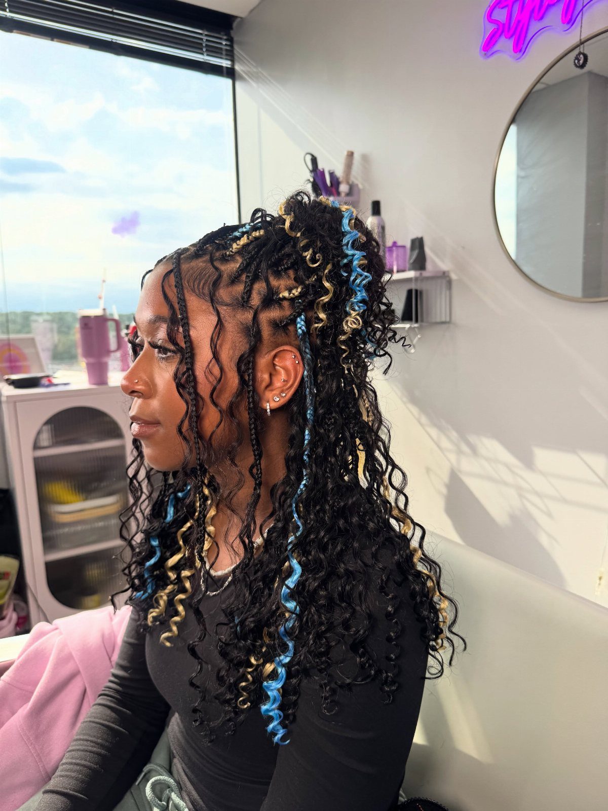 Woman with curly black hair featuring bold blue and blonde highlights in profile.
