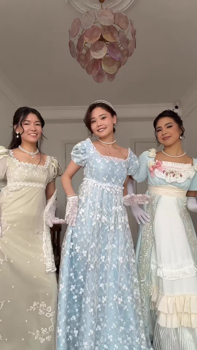 Three women wearing Regency-style gowns in pale green and light blue floral patterns.