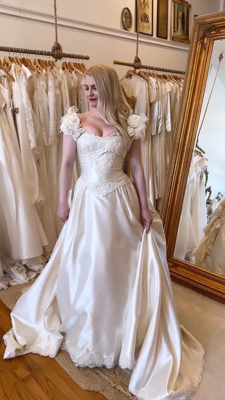 Woman in a white satin bridal gown with a structured bodice in a shop