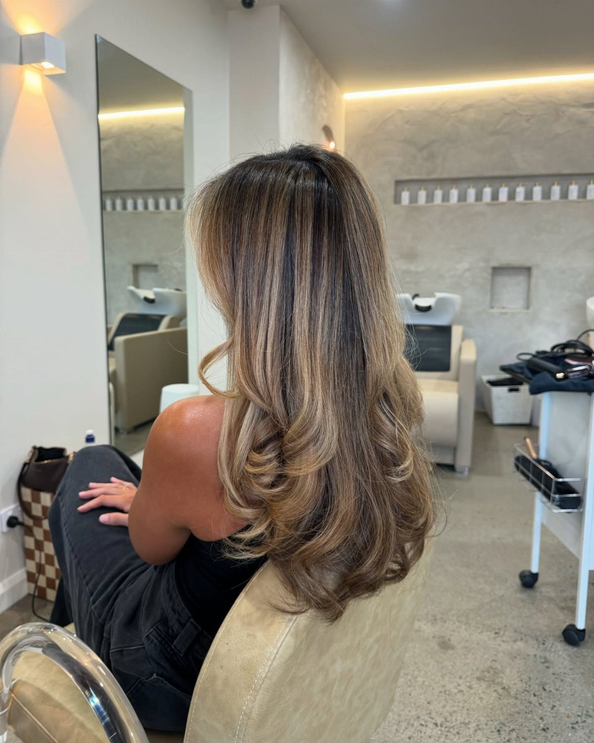 Long wavy brown hair with bright blonde babylights in a modern hair salon.