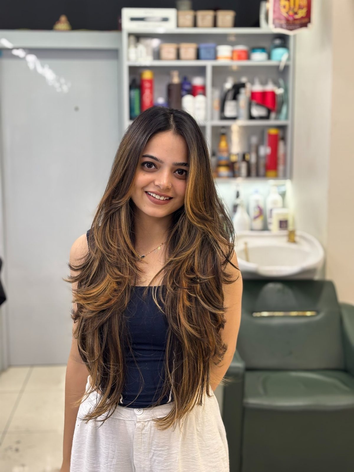 Woman with long brown hair and golden blonde highlights posing in a salon