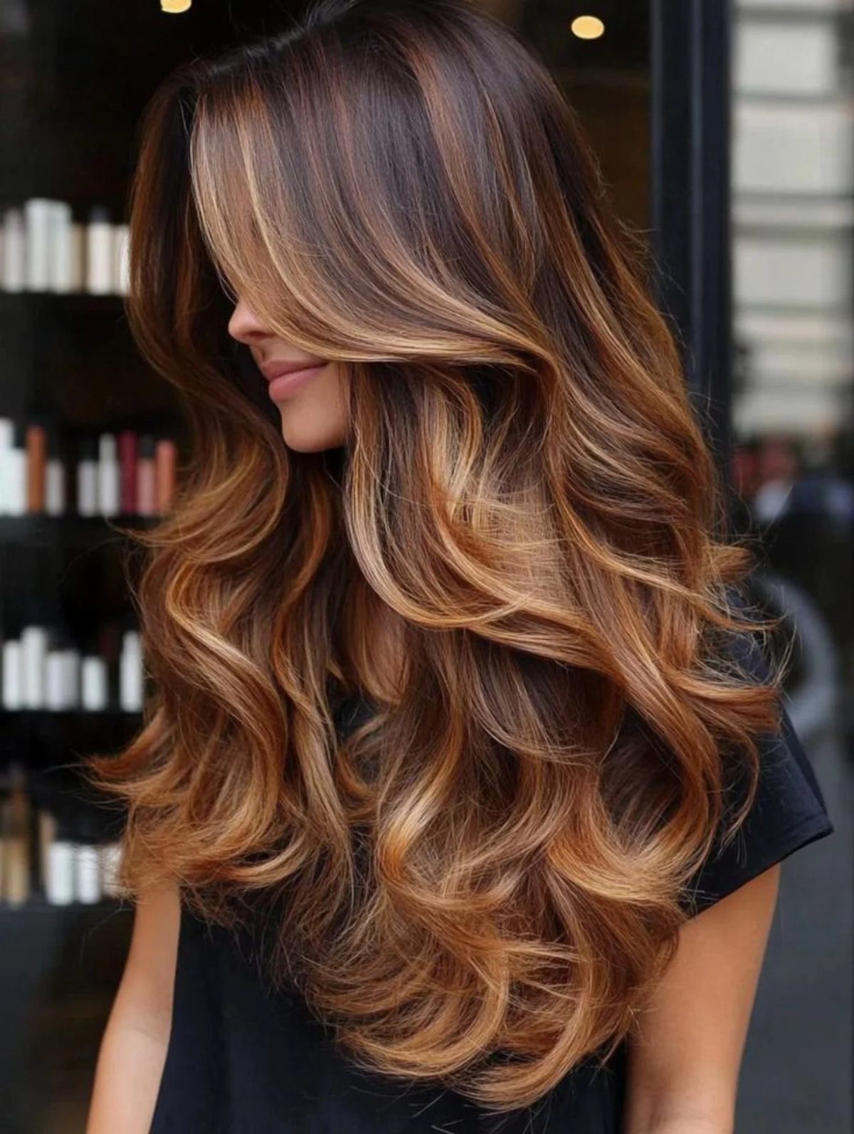 Woman with long wavy brown hair and chunky golden blonde balayage highlights.