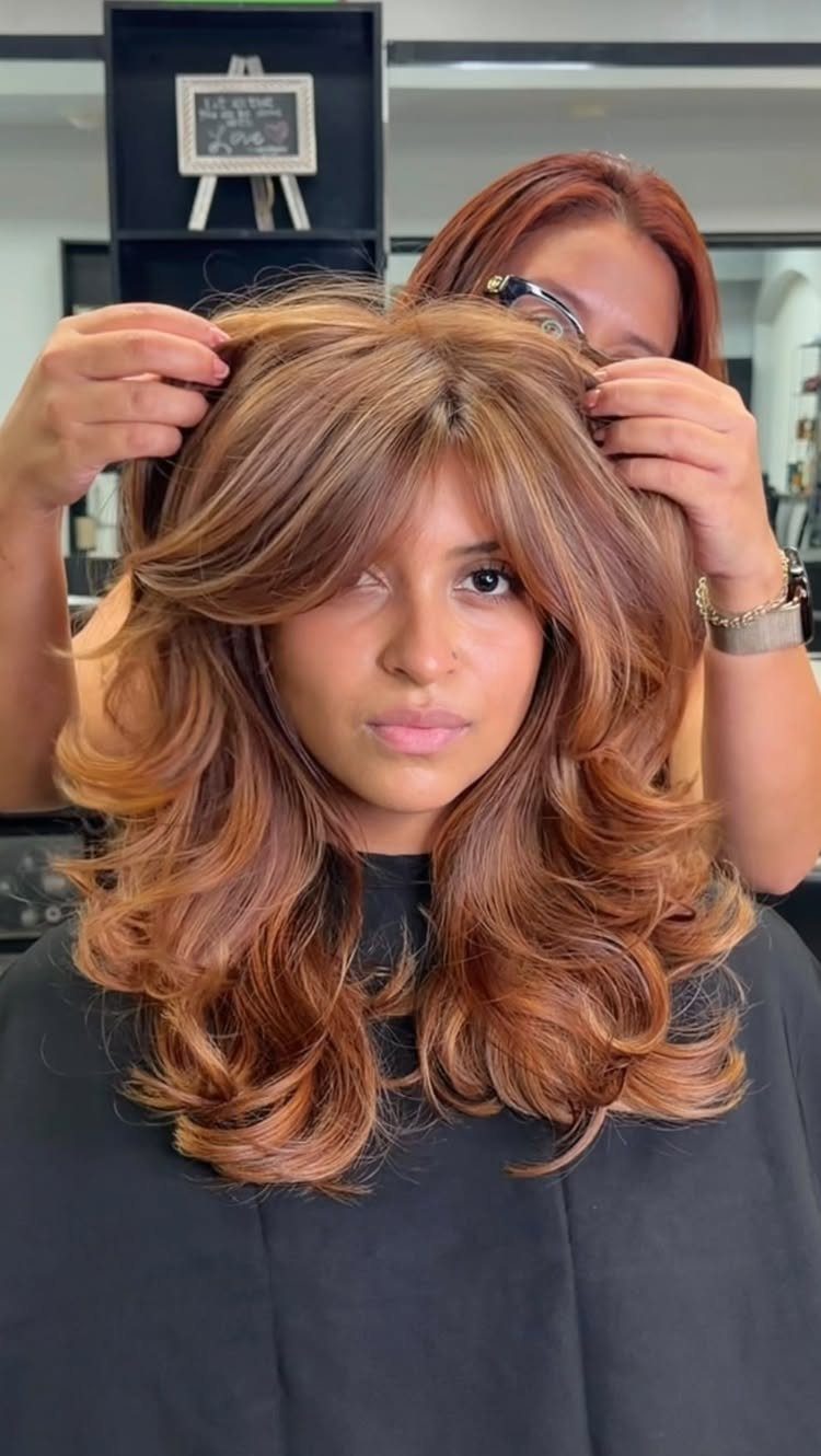 Woman with long wavy ginger and honey blonde balayage hair in a salon